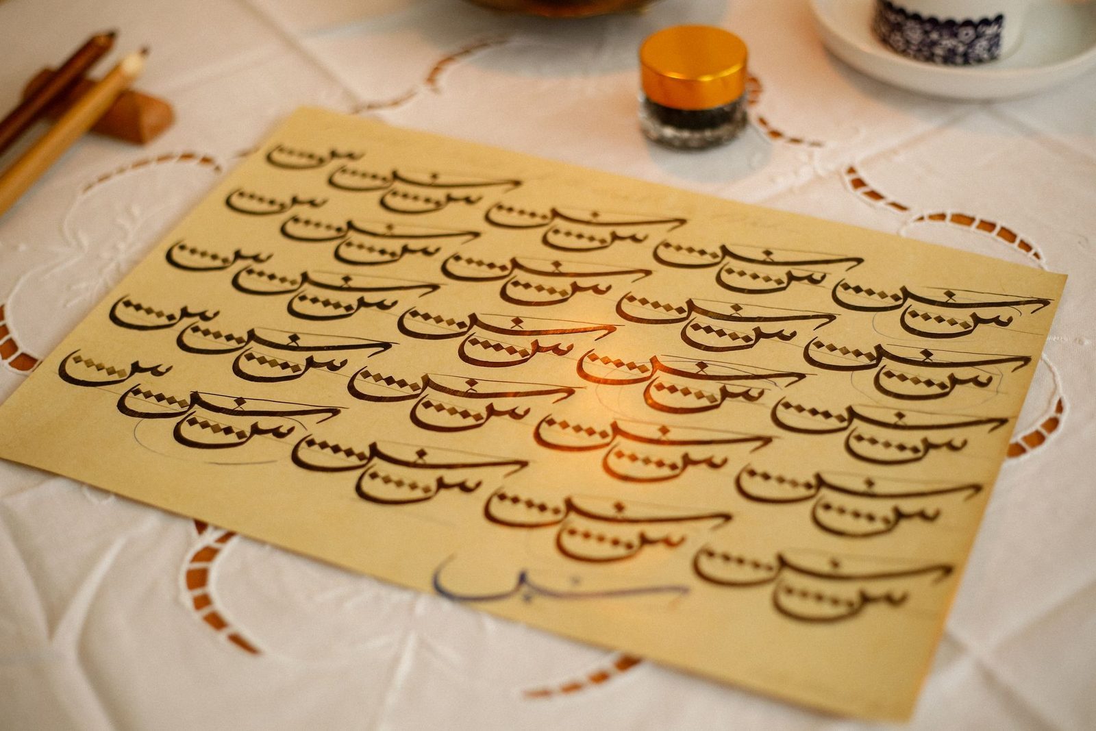Calame en roseau et encre noire posés sur un papier orné de calligraphie arabe