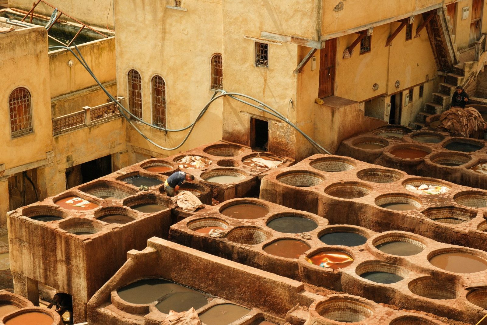 Tanneur travaillant dans une cuve de la tannerie de Chouara, entouré de cuves de teinture