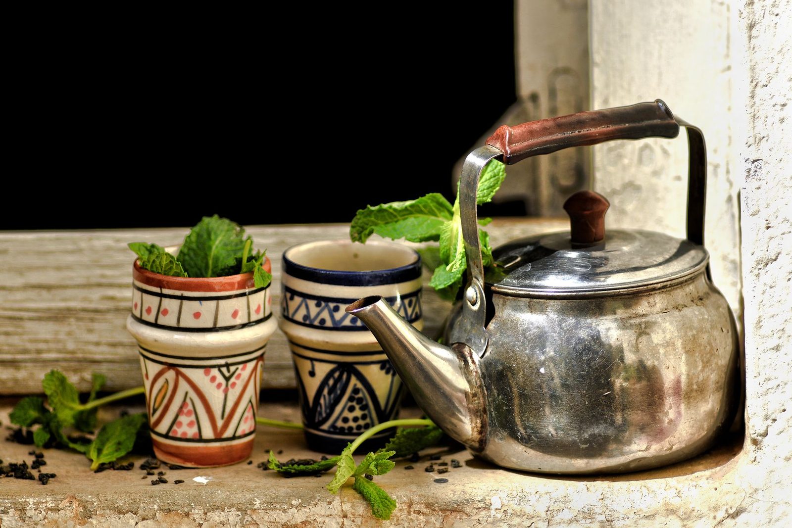 Plateau de thé marocain avec théière, verres colorés et menthe fraîche